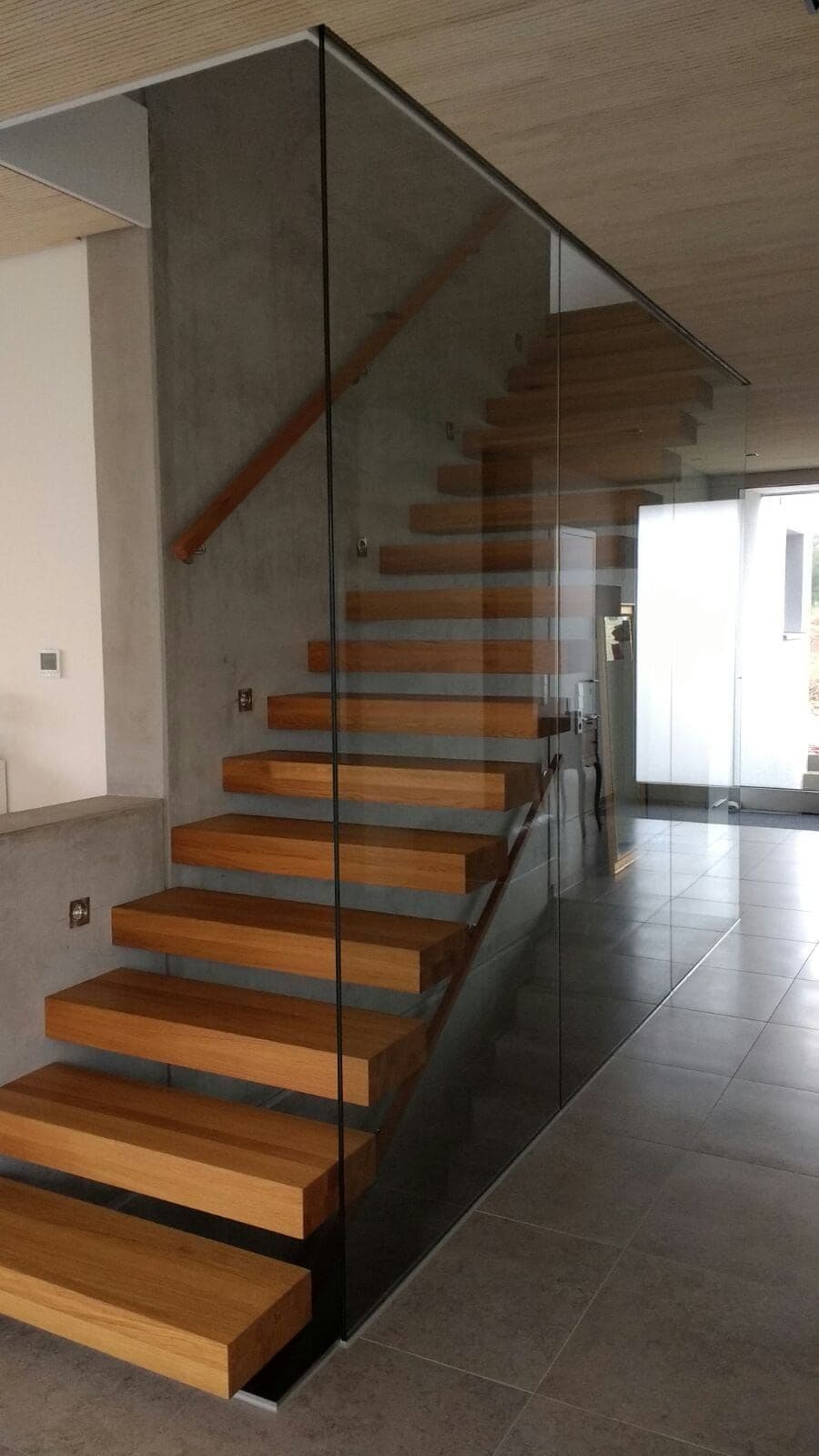 Freitragende Treppe aus Eichenholz mit Stahlträger und Glaswand, gefertigt von Maier Metallbau in Ulm