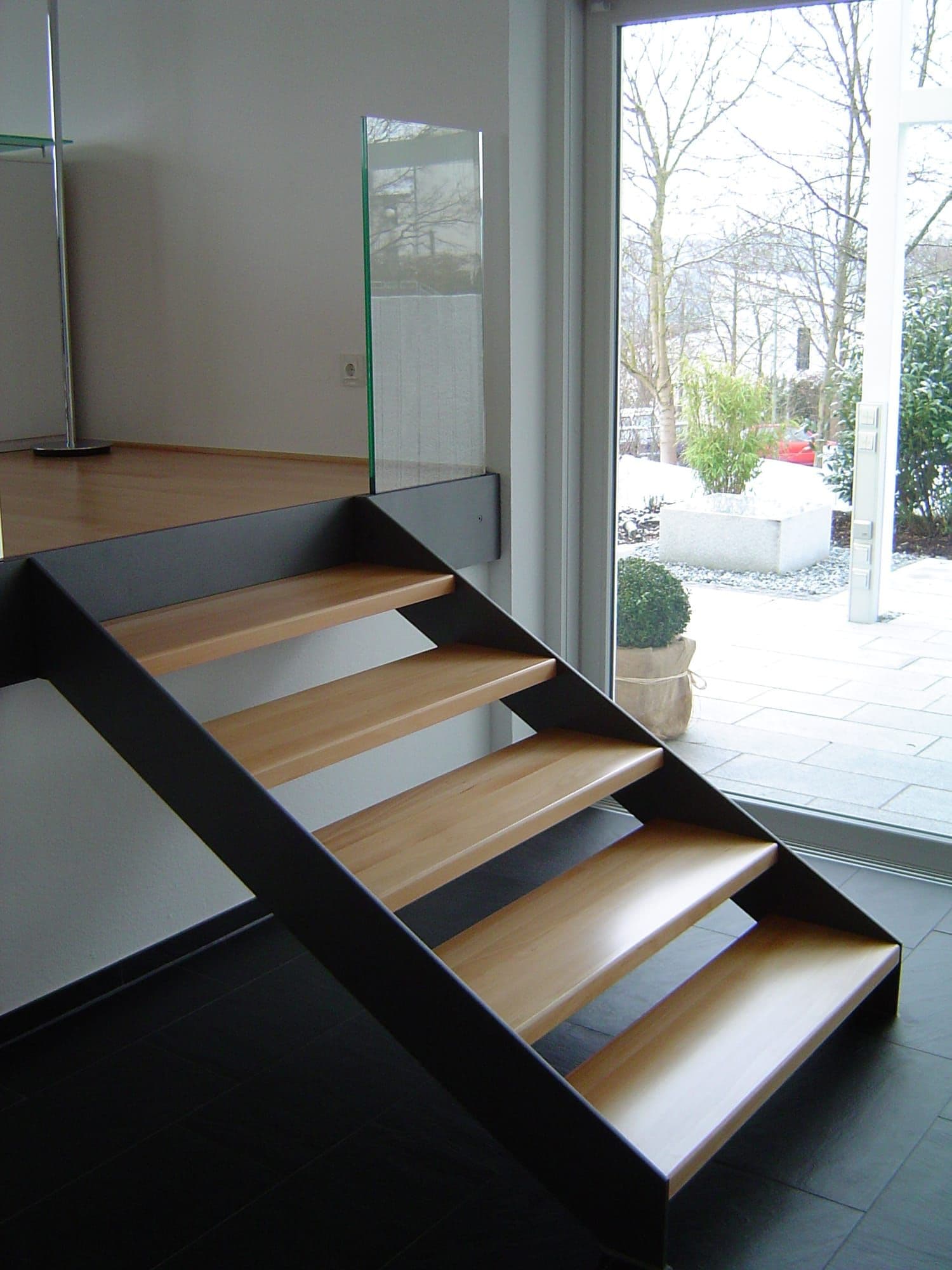 Moderne Stahl-Holz-Treppe mit schwarzem Stahlwangenträger von Maier Metallbau